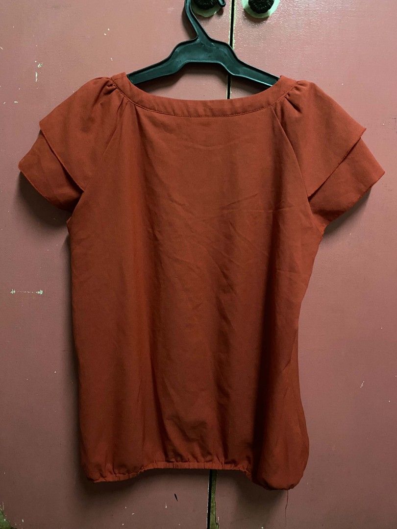 Sakaya Rusty Orange Ruffle Blouse Top (Category: Blouses) located in Paranaque City. Submitted by zackzero (Listing ID 1467226266, Image 2). Description: - Brand: Sakaya - Color: Rusty orange - Design: Layered ruffle sleeves and neckline detail - Fit: Scoop neckline with an elastic hem for a gathered look - Material: Soft and lightweight fabric - Style: Great casual top for daily outfits.