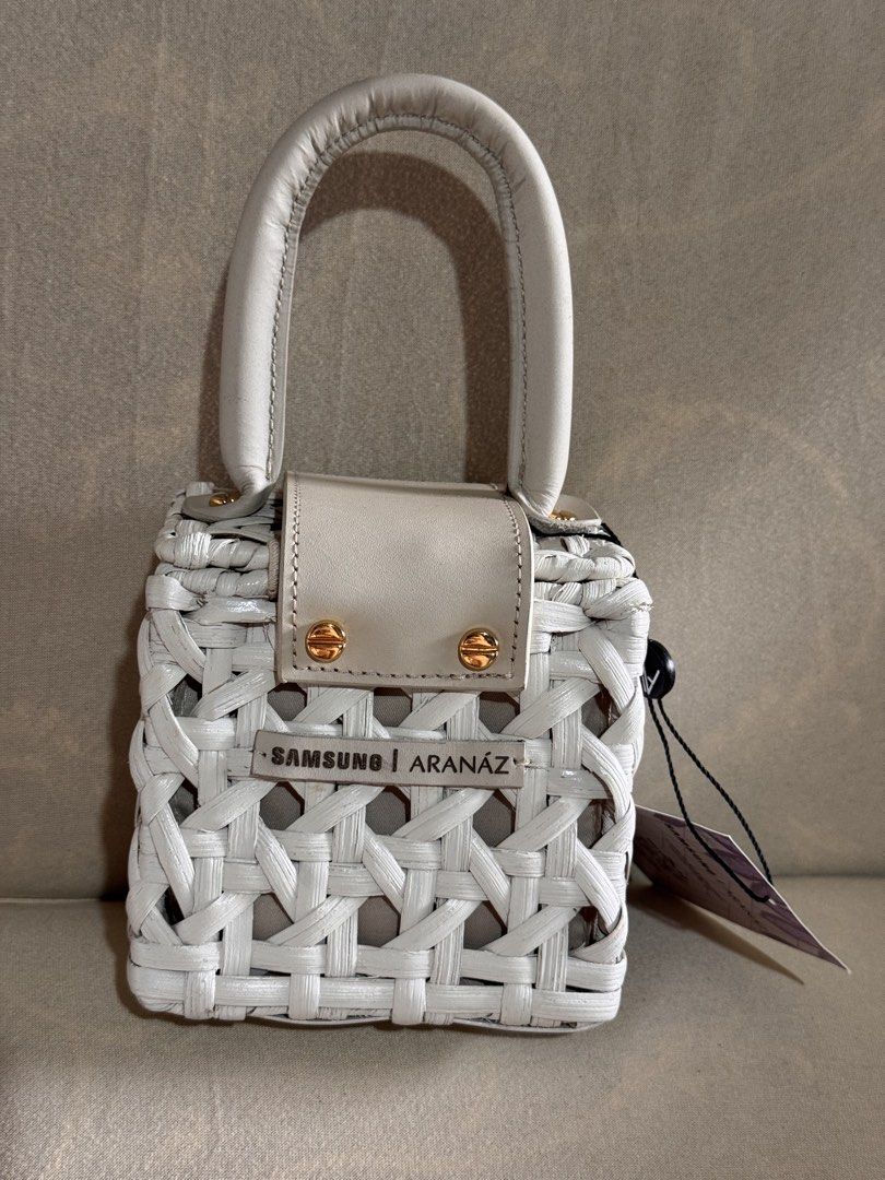 Samsung x Aranaz Mini Charlie Bag (Category: Cross-body Bags) located in Marikina City. Submitted by 1stuffshop (Listing ID 1467182817, Image 2). Description: - Brand: Samsung x Aranaz - Style: Mini Charlie Bag - Design: Handcrafted white woven with gold hardware and front metal plaque - Closure: Magnetic closure with top handle - Extras: Includes original tag and detachable strap.