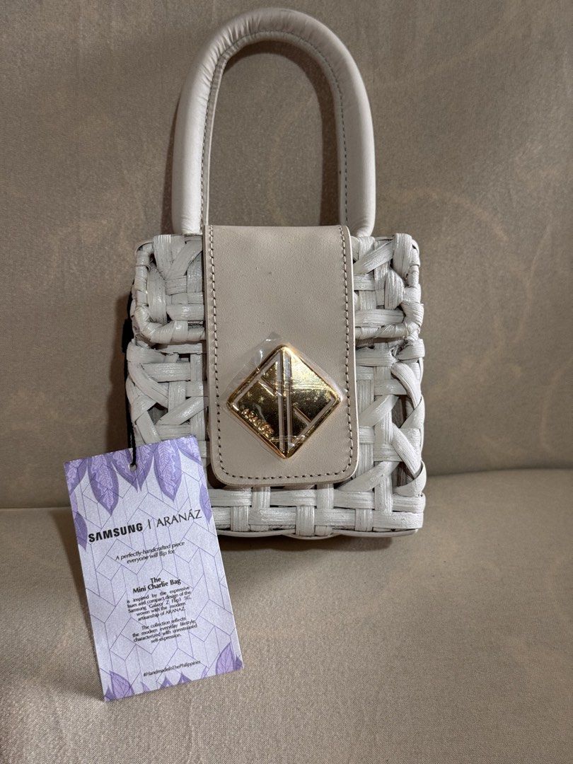 Samsung x Aranaz Mini Charlie Bag (Category: Cross-body Bags) located in Marikina City. Submitted by 1stuffshop (Listing ID 1467182817, Image 1). Description: - Brand: Samsung x Aranaz - Style: Mini Charlie Bag - Design: Handcrafted white woven with gold hardware and front metal plaque - Closure: Magnetic closure with top handle - Extras: Includes original tag and detachable strap.