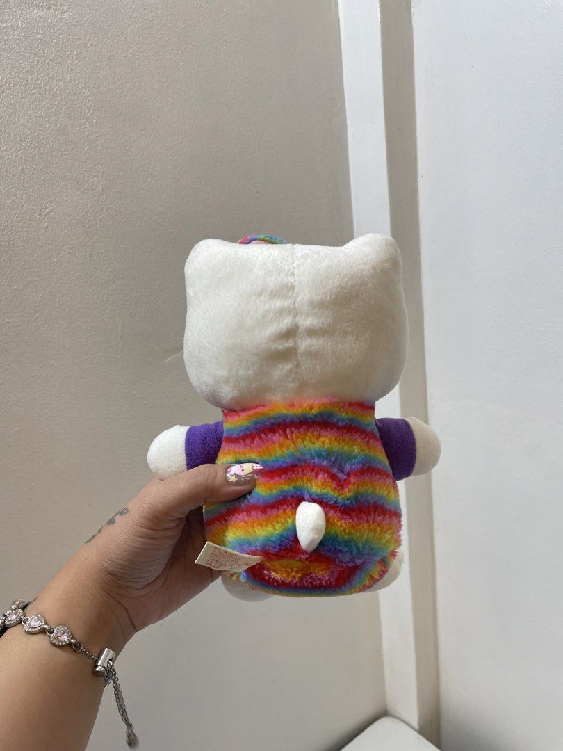 Sanrio Hello Kitty Eikoh Rainbow Plush Toy (Category: Plushies & Soft Toys) located in Iba. Submitted by wealtheallymari99 (Listing ID 1467268574, Image 3). Description: - Brand: Eikoh (Sanrio Official) - Character: Kitty Plush - Outfit: Rainbow tie-dye with purple sleeves and matching hair accessory - Details: Red apple emblem with Kitty text, embroidered black eyes and whiskers, yellow nose - Condition: Brand new with original back tag and webs