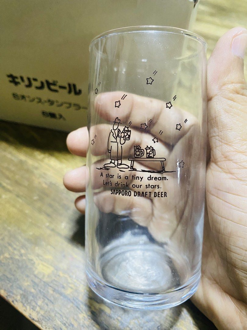 Sapporo Draft Beer & Kirin Beer Set (Category: Coffee & Tea Tableware) located in San Jose del Monte. Submitted by cityhanter007 (Listing ID 1467324805, Image 1). Description: - Set of 5 ounce clear glass tumblers from Kirin Brewery Company - Features a whimsical illustration of a man and table with the quote "A star is a tiny dream. Let's drink our stars. Sapporo Draft Beer" - Includes original white box with Japanese text on the side - Excellen