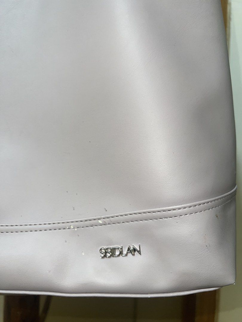 SSIDLAN Light Purple Tote Bag (Category: Tote Bags) located in Manila. Submitted by goldenwater_a772ad (Listing ID 1467195369, Image 3). Description: - Brand: SSIDLAN - Color: Light purple / Solid - Material: Faux leather - Features: Spacious interior, secure zipper closure, comfortable shoulder straps, silver-toned brand lettering - Condition: Minor scuffs and marks on the lower front near the logo - Perfect for: Work, school, or casual daily us