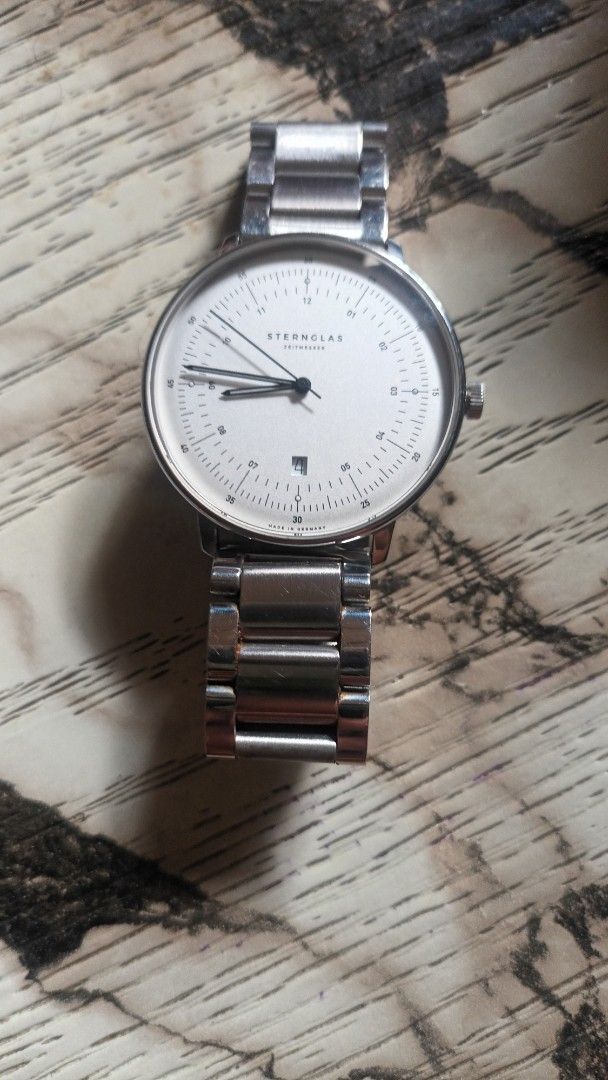 Sternglas Zeitmesser Watch (Category: Men's Watches) located in Imus. Submitted by daviddm9260 (Listing ID 1467178003, Image 2). Description: - Brand: Sternglas (German minimalist design) - Dial: White with slim black hands, clear minute markers, and date. window at 3 o'clock - Crown: Unique top position placement. - Strap: Stainless steel linked bracelet with secure butterfly clasp - Style: Clean Bauhaus aesthetic, ideal for everyday wear. -Maid