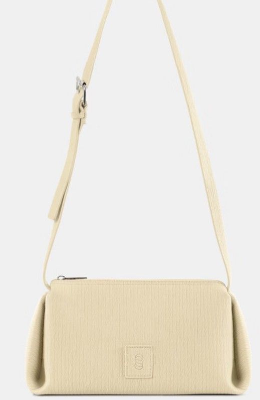 Straightforward Solenne Bag (Category: Shoulder Bags) located in Caloocan City. Submitted by glynneb (Listing ID 1467330761, Image 1). Description: - Color: Cream - Finish: Textured throughout with folded side gussets for a clean, structured shape - Closure: Secure zip-top closure - Hardware: Silver-toned with an adjustable strap - Branding: Small square patch logo embossed on the lower front center - Condition: Brand new / Excellent quality - Pe