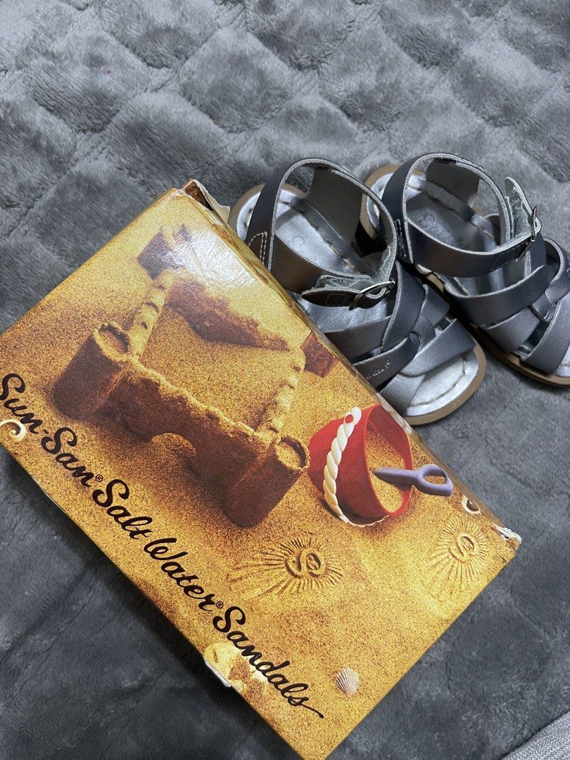 Sun-San Salt Water Sandals (Category: Babies & Kids Fashion) located in Lipa City. Submitted by kissesann (Listing ID 1467298102, Image 3). Description: - Brand: Sun-San Salt Water Sandals - Style: Classic woven strap with adjustable ankle buckle - Color: Pewter (metallic greyish silver) - Material: Genuine leather upper with cushioned sole - Size: 6 (indicated on box) - Inclusions: Original box with fitting instructions included - Condition: Exc