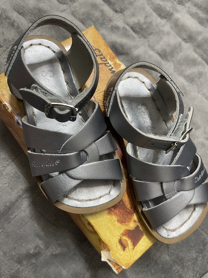 Sun-San Salt Water Sandals (Category: Babies & Kids Fashion) located in Lipa City. Submitted by kissesann (Listing ID 1467298102, Image 2). Description: - Brand: Sun-San Salt Water Sandals - Style: Classic woven strap with adjustable ankle buckle - Color: Pewter (metallic greyish silver) - Material: Genuine leather upper with cushioned sole - Size: 6 (indicated on box) - Inclusions: Original box with fitting instructions included - Condition: Exc