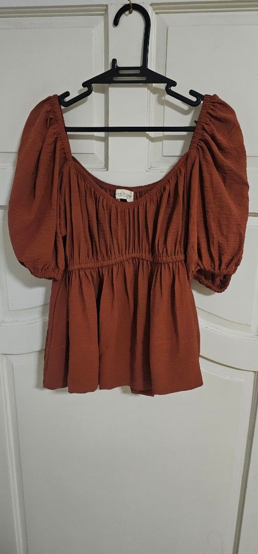 TAYO STUDIO Rust Orange Puff Sleeve Top Size 2 (Category: Blouses) located in Davao. Submitted by sachigo (Listing ID 1467261443, Image 1). Description: - Brand: KYD Studio - Size: 2 - Color: Rust / Earthy burnt orange - Design: Square neckline, gathered shirred bodice, short puff sleeves, flared peplum hem - Fabric: Textured with a slight crinkle effect - Condition: Excellent, easy to match with denim or skirts used 1 hr only by the model.