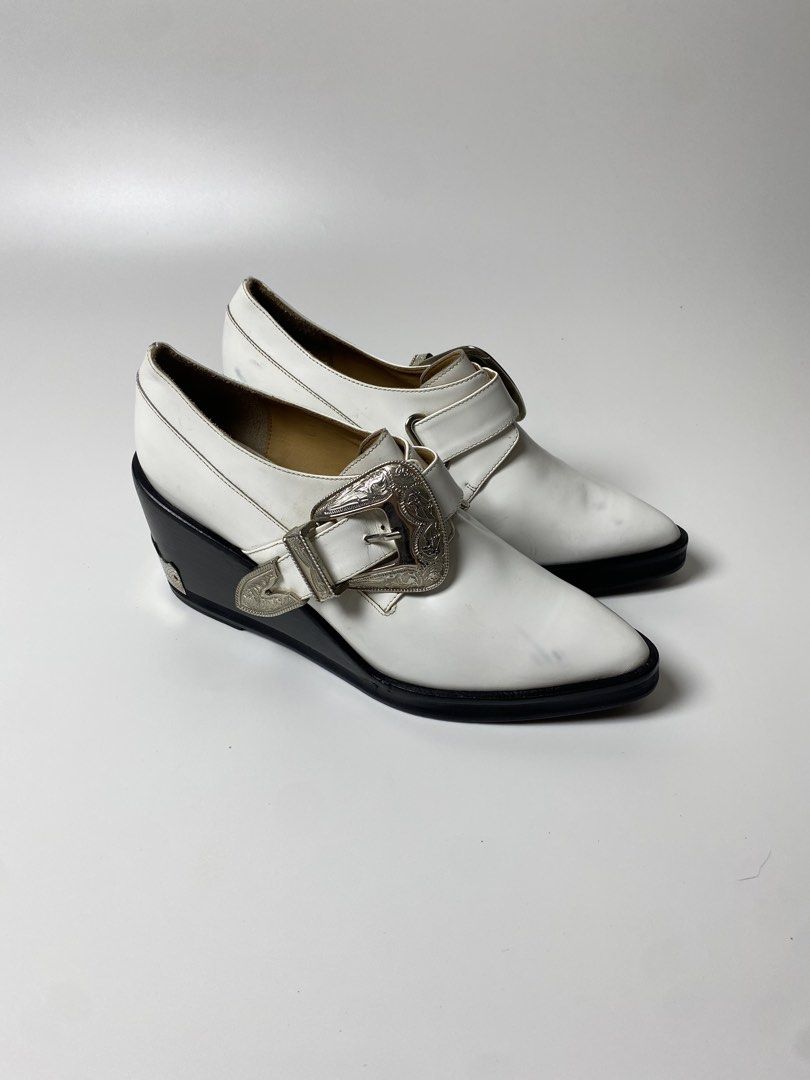 TOGA PULLA BUCKLED OXFORD WEDGES (Category: Boots) located in Balanga. Submitted by faded_garmz (Listing ID 1467282181, Image 1). Description: TOGA PULLA BUCKLED OXFORD WEDGES A striking twist on a classic footwear silhouette, combining traditional menswear-inspired tailoring with a distinct Western aesthetic. Crafted with a premium smooth white leather upper, these shoes feature a structured almond toe and a modern, angular black wedge heel that