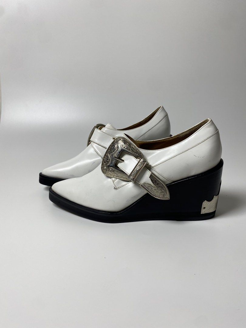 TOGA PULLA BUCKLED OXFORD WEDGES (Category: Boots) located in Balanga. Submitted by faded_garmz (Listing ID 1467282181, Image 2). Description: TOGA PULLA BUCKLED OXFORD WEDGES A striking twist on a classic footwear silhouette, combining traditional menswear-inspired tailoring with a distinct Western aesthetic. Crafted with a premium smooth white leather upper, these shoes feature a structured almond toe and a modern, angular black wedge heel that