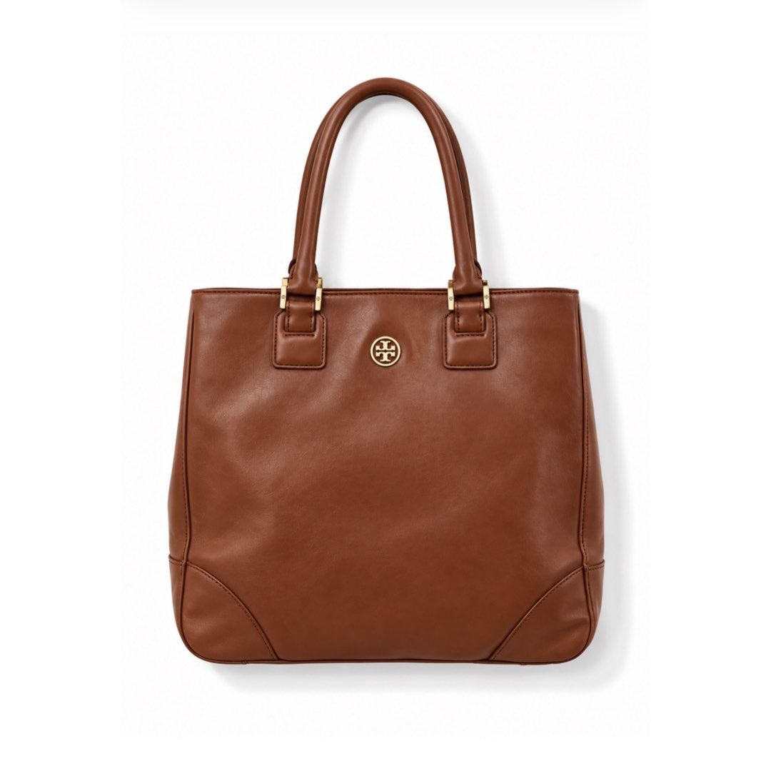Tory Burch Brown Leather Tote Bag (Category: Tote Bags) located in Cavite. Submitted by vanity_isme (Listing ID 1467195532, Image 1). Description: - Brown leather Tory Burch tote - Elegant gold-tone hardware and signature front logo medallion - Comfortable double top handles with detailed stitching - Spacious fabric-lined interior with secure zip pocket and slip pockets - Structured shape with reinforced corners for added durability - Signs of we