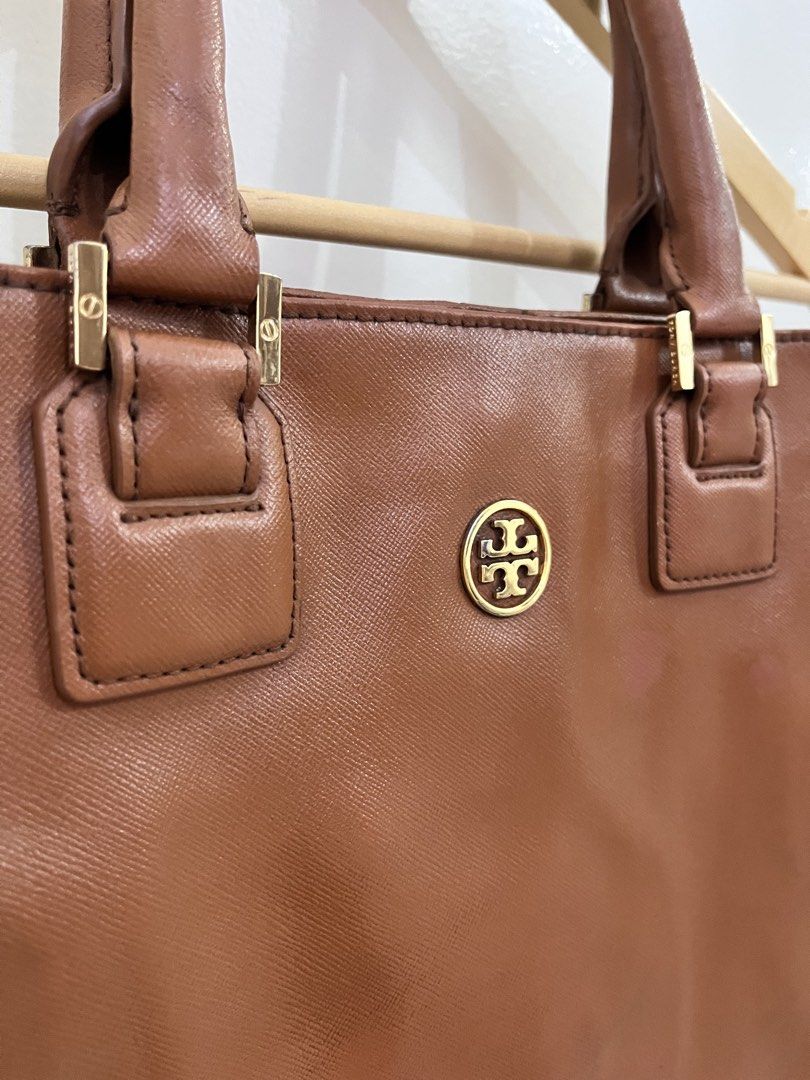 Tory Burch Brown Leather Tote Bag (Category: Tote Bags) located in Cavite. Submitted by vanity_isme (Listing ID 1467195532, Image 2). Description: - Brown leather Tory Burch tote - Elegant gold-tone hardware and signature front logo medallion - Comfortable double top handles with detailed stitching - Spacious fabric-lined interior with secure zip pocket and slip pockets - Structured shape with reinforced corners for added durability - Signs of we