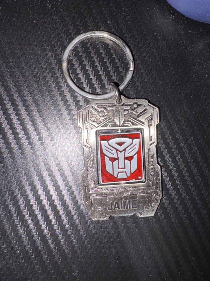 Transformers Universal Studios 2013 Hasbro Spinning Keychain (Category: Character Goods) located in Quezon City. Submitted by colonelbirb (Listing ID 1467350840, Image 3). Description: - Official Universal Studios Transformers merchandise (2013 Hasbro China) - Heavy metal build with a fun spinning centerpiece - Dual-sided: Red/silver Autobot logo on one side, purple/silver Decepticon logo on the other - Personalized with a custom engraved 'Jaime'