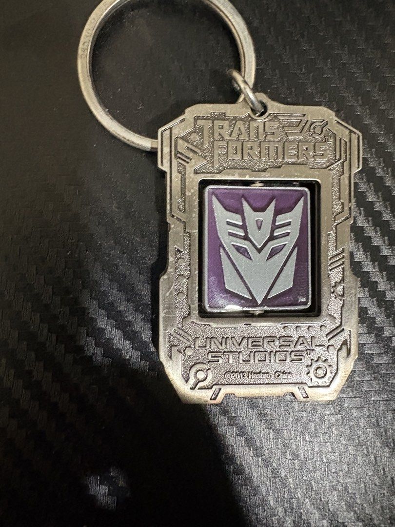 Transformers Universal Studios 2013 Hasbro Spinning Keychain (Category: Character Goods) located in Quezon City. Submitted by colonelbirb (Listing ID 1467350840, Image 2). Description: - Official Universal Studios Transformers merchandise (2013 Hasbro China) - Heavy metal build with a fun spinning centerpiece - Dual-sided: Red/silver Autobot logo on one side, purple/silver Decepticon logo on the other - Personalized with a custom engraved 'Jaime'