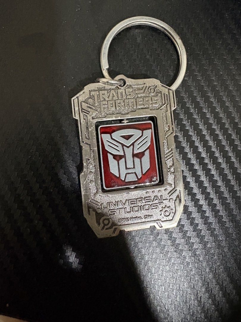 Transformers Universal Studios 2013 Hasbro Spinning Keychain (Category: Character Goods) located in Quezon City. Submitted by colonelbirb (Listing ID 1467350840, Image 1). Description: - Official Universal Studios Transformers merchandise (2013 Hasbro China) - Heavy metal build with a fun spinning centerpiece - Dual-sided: Red/silver Autobot logo on one side, purple/silver Decepticon logo on the other - Personalized with a custom engraved 'Jaime'