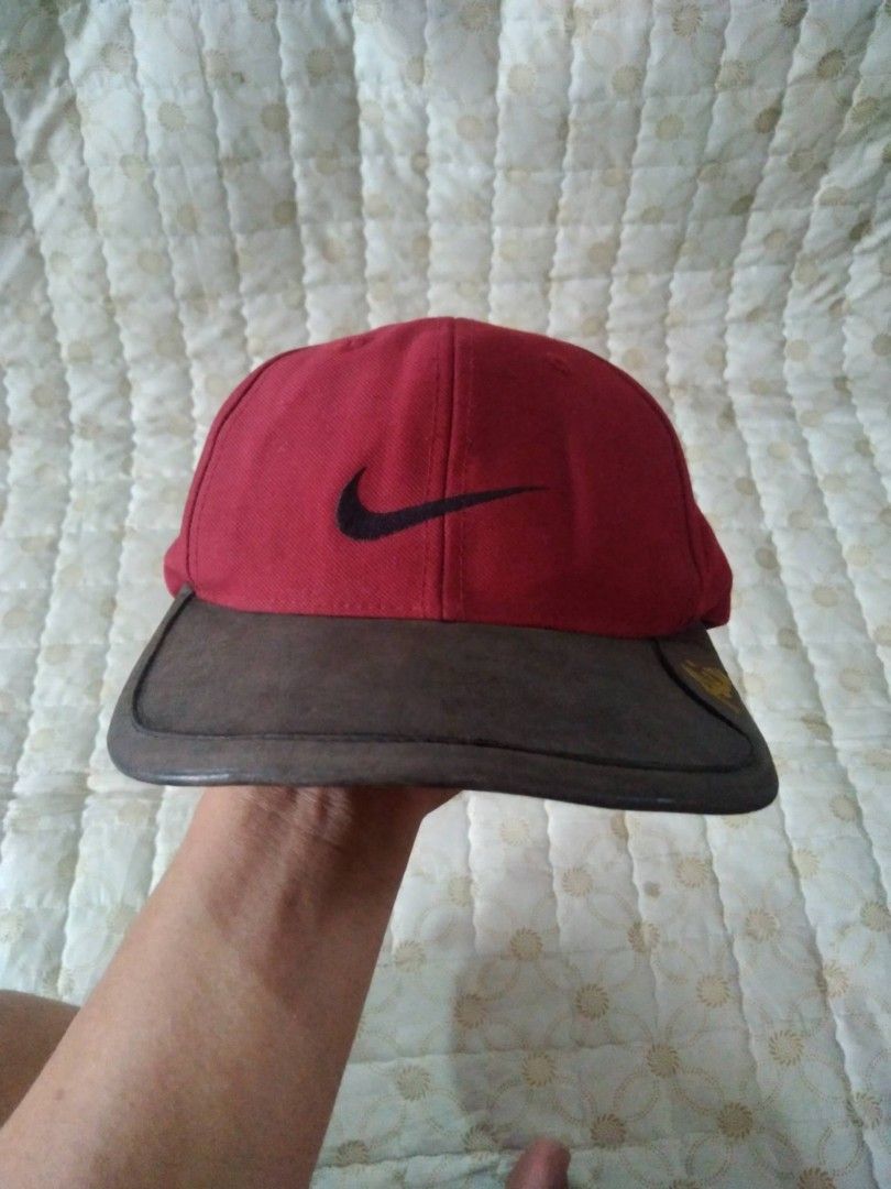 Vintage 90's Nike Air Red Cap (Category: Caps & Hats) located in Zamboanga. Submitted by nurbya898048 (Listing ID 1467260514, Image 1). Description: This is a vintage 1990s Nike Air cap 6 panel. Bown leather brim featuring embroidered Air text on the side. Black swoosh embroidered on the front panels. Adjustable leather strap at the back with metal buckle. Classic unstructured dad hat shape. .