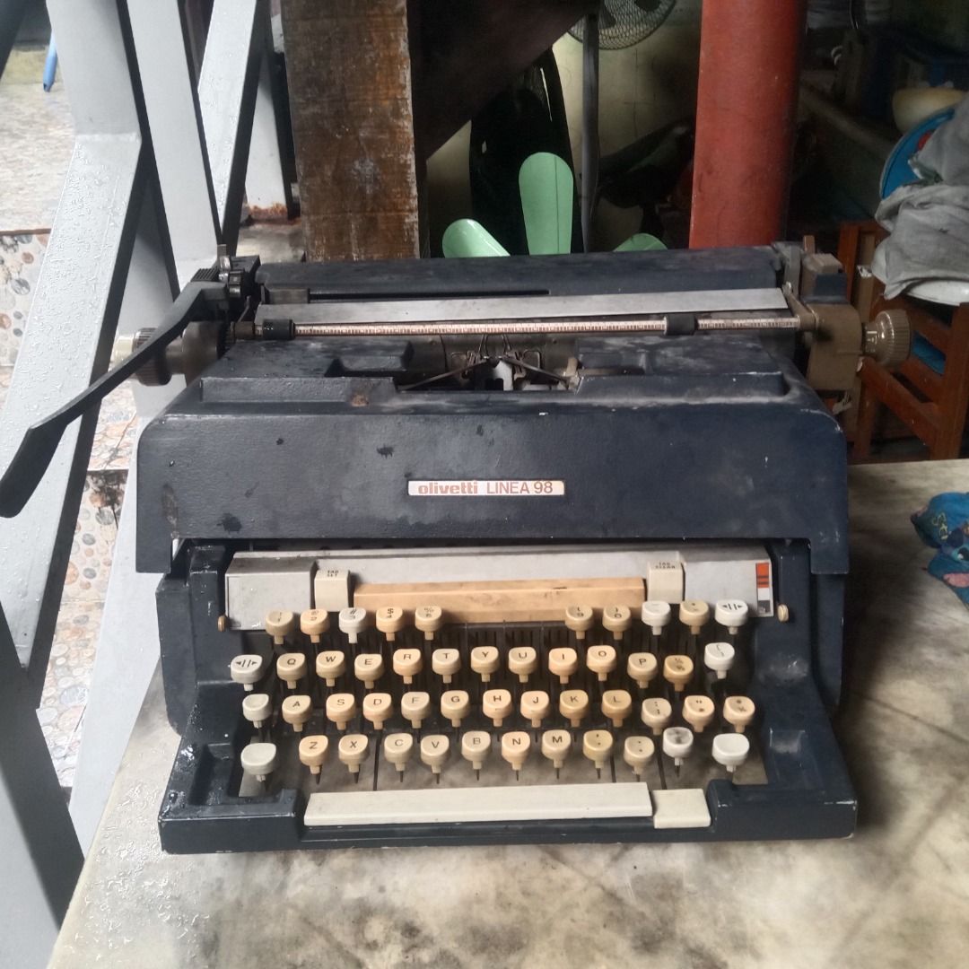 Vintage Olivetti Linea 98 Typewriter (Category: Office & Business Technology) located in Manila. Submitted by louiebox05 (Listing ID 1467266983, Image 2). Description: - Model: Vintage Olivetti Linea 98 heavy manual desktop typewriter - Color: Classic dark blue - Layout: Standard QWERTY - Condition: Shows heavy dust and storage wear, but all keys and levers are intact; requires cleaning and a new ribbon - Shipping: Heavy item, pick-up preferred o