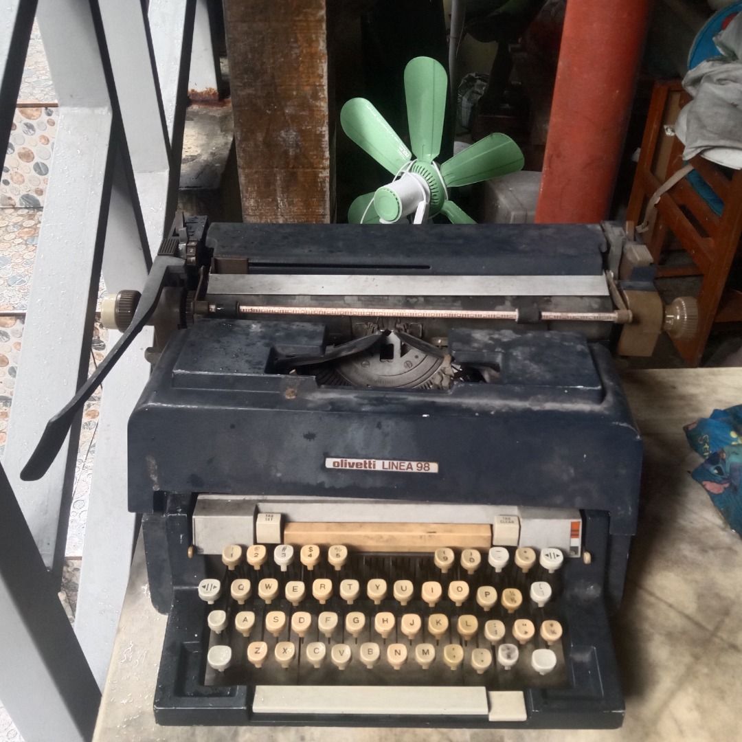 Vintage Olivetti Linea 98 Typewriter (Category: Office & Business Technology) located in Manila. Submitted by louiebox05 (Listing ID 1467266983, Image 1). Description: - Model: Vintage Olivetti Linea 98 heavy manual desktop typewriter - Color: Classic dark blue - Layout: Standard QWERTY - Condition: Shows heavy dust and storage wear, but all keys and levers are intact; requires cleaning and a new ribbon - Shipping: Heavy item, pick-up preferred o