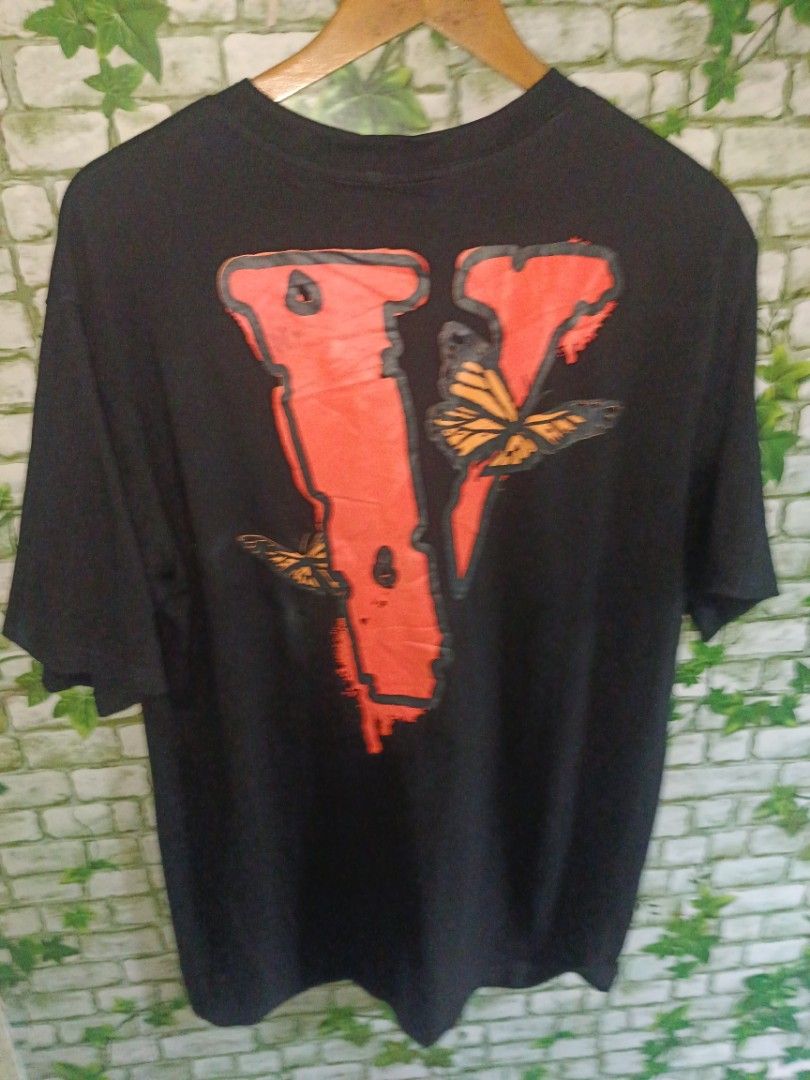 Vlone Juice WRLD Legends Never Die Tee Black (Category: Tshirts & Polo Shirts ) located in Carcar. Submitted by rolandobac92675 (Listing ID 1467357946, Image 3). Description: Vlone x Juice WRLD Legends Never Die t-shirt in black. Large red V logo on the back with orange butterflies. Small text print on the front chest reading legends never die with an orange V. Made in USA tag inside collar. Heavy cotton material..