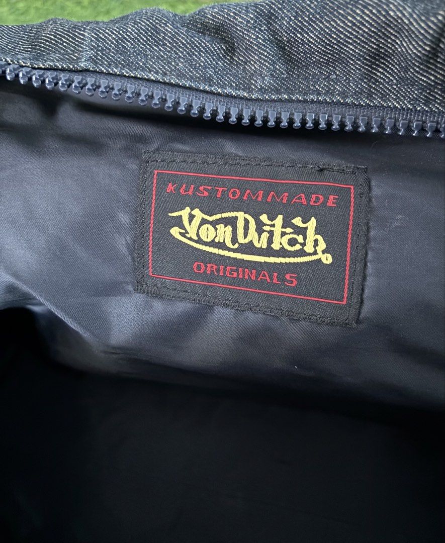 Von Dutch Denim Handbag (Category: Shoulder Bags) located in Makati City. Submitted by rare_thrift_stuff (Listing ID 1467206744, Image 3). Description: - Brand: Von Dutch - Material: Dark wash denim with dark blue faux leather handles - Details: Iconic white piping trim, large white front logo graphic, and red Kustommade Originals interior patch - Closure: Secure top zip closure - Interior: Black fabric lining - Condition: Excellent pre-loved con