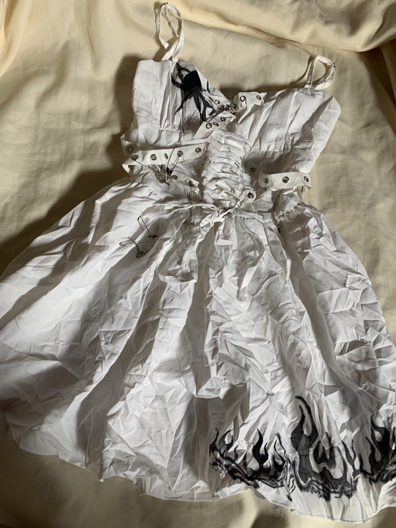 White Alternative Goth Spider Flame Corset Dress (Category: Dresses) located in Davao. Submitted by cheineebau09680 (Listing ID 1467210950, Image 1). Description: - Style: White alternative mini dress - Size: Small - Material: 100% polyester - Details: Spider graphic near neckline, flame print along the hem - Back: Lace-up corset back with grommets and straps - Accents: Silver safety pins and hanging cross charms with chains - Care: Hand wash onl