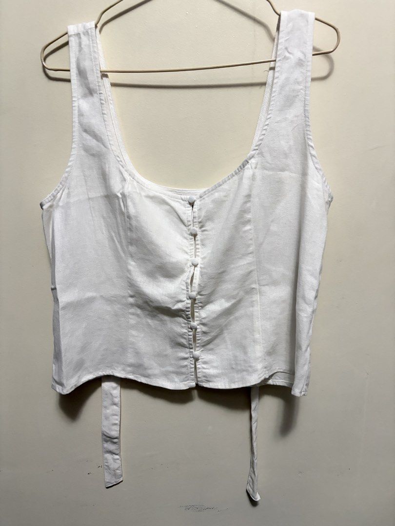 White button front crop tank top with back tie (Category: Sleeveless) located in Quezon City. Submitted by j.steffy (Listing ID 1467323249, Image 1). Description: - Color: Clean solid white - Style: Cropped tank top with scoop neckline and thick shoulder straps - Details: Functional front buttons and self-tie ribbon at the back waist - Fit: Sleeveless, light, and casual - Condition: Brand new / Excellent - Perfect for: Warm weather days or stylis