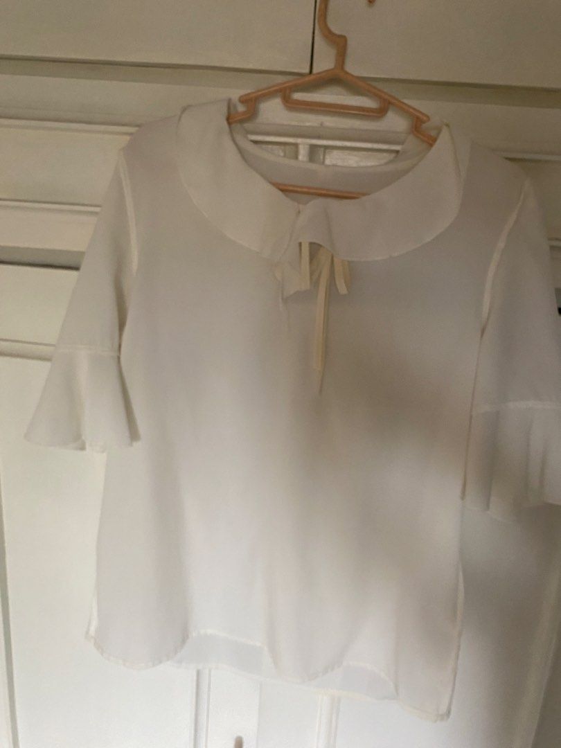 White Chiffon Top (L on tag) (Category: Blouses) located in Manila. Submitted by danie_sells (Listing ID 1467277513, Image 2). Description: - Color: White - Material: Light and breathable chiffon - Details: Rounded collar with neck tie string - Sleeves: Half sleeves with flared ruffle cuffs - Versatility: Perfect for work or casual outings, easy to pair with skirts or trousers - Issue: Slight discoloration on the ribbon - Negotiable! ——— Bust: 96