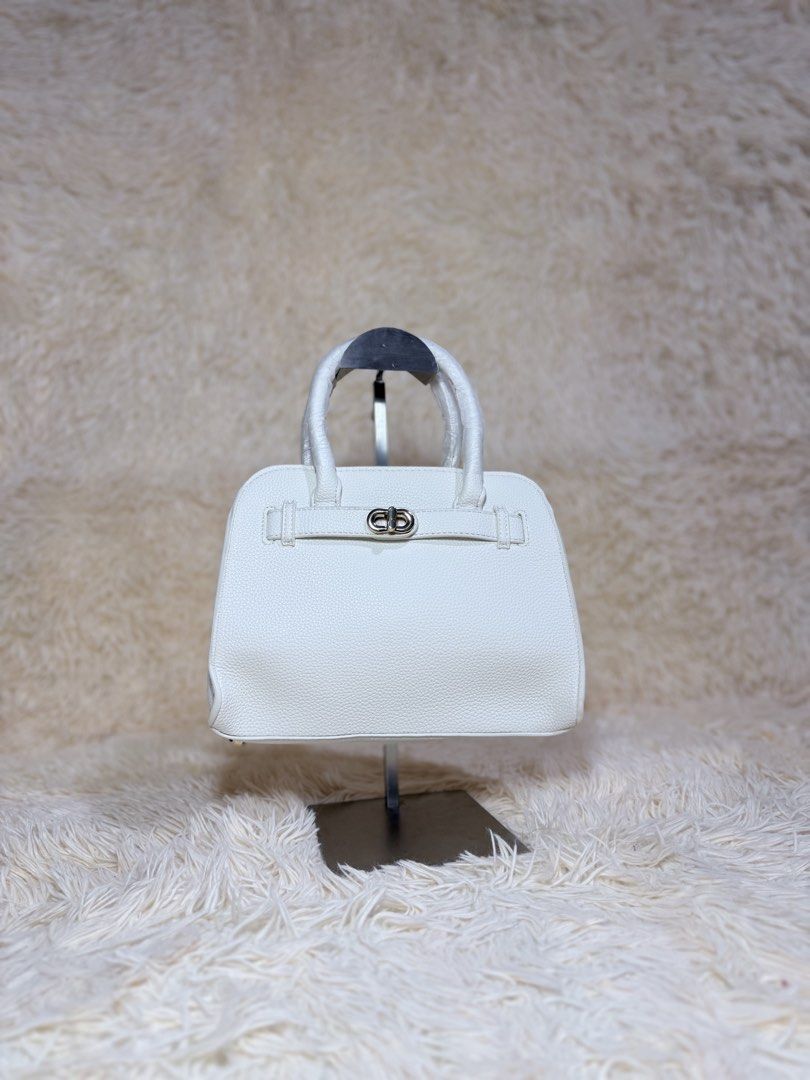 White Leather Handbag with Silver Hardware (Category: Luxury Bags & Wallets) located in Caloocan City. Submitted by hirahira.co (Listing ID 1467281174, Image 1). Description: - Style: Minimalist and compact top handle handbag - Material: Premium white pebbled leather - Hardware: Elegant silver-tone front closure strap - Condition: Brand new with handles still wrapped in protective material - Quality: Structured flat base with clean, neat edge sti