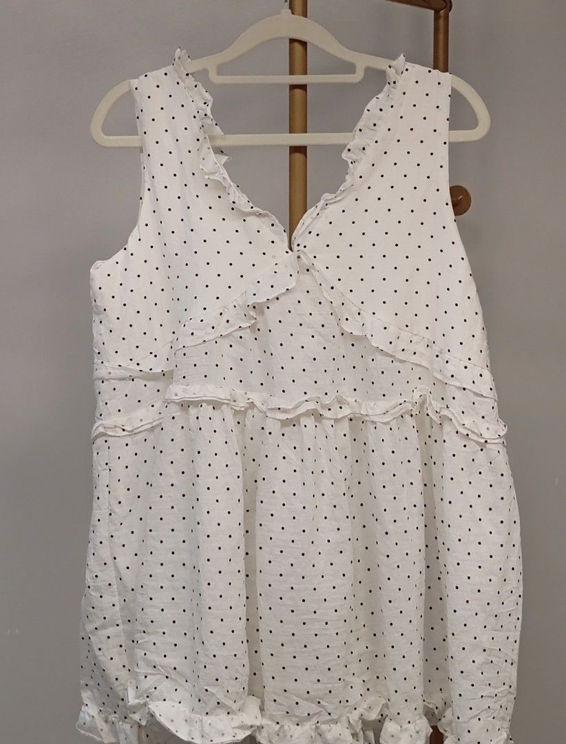White Polka Dot Ruffle Sleeveless Blouse (Category: Sleeveless) located in Kananga. Submitted by aurylien.clo (Listing ID 1467194800, Image 1). Description: - medium to large - Color/Pattern: Classic white with black polka dots - Design: Sleeveless with ruffled V-neck and tiered front ruffles - Fit: Relaxed babydoll fit with a flared hem - Material: Lightweight, textured swiss dot fabric - Style Tip: Great for warm weather; easy to dress up or do