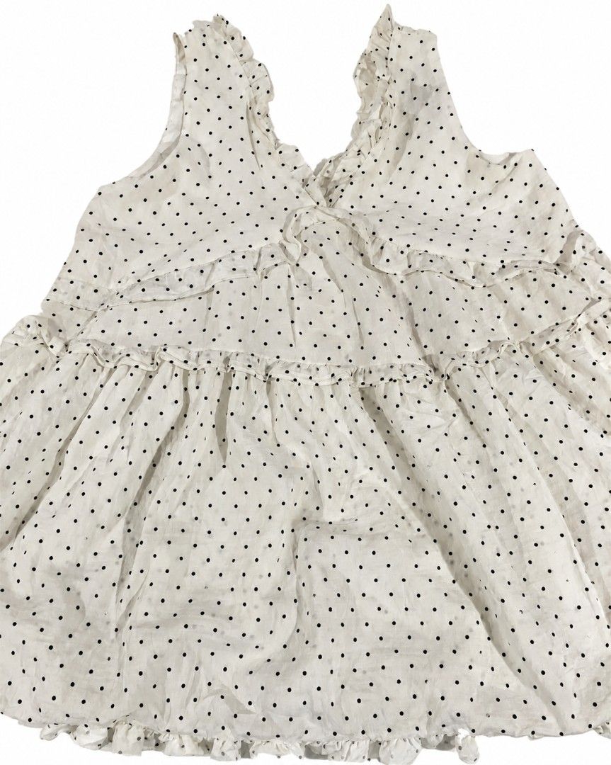 White Polka Dot Ruffle Sleeveless Blouse (Category: Sleeveless) located in Kananga. Submitted by aurylien.clo (Listing ID 1467194800, Image 2). Description: - medium to large - Color/Pattern: Classic white with black polka dots - Design: Sleeveless with ruffled V-neck and tiered front ruffles - Fit: Relaxed babydoll fit with a flared hem - Material: Lightweight, textured swiss dot fabric - Style Tip: Great for warm weather; easy to dress up or do