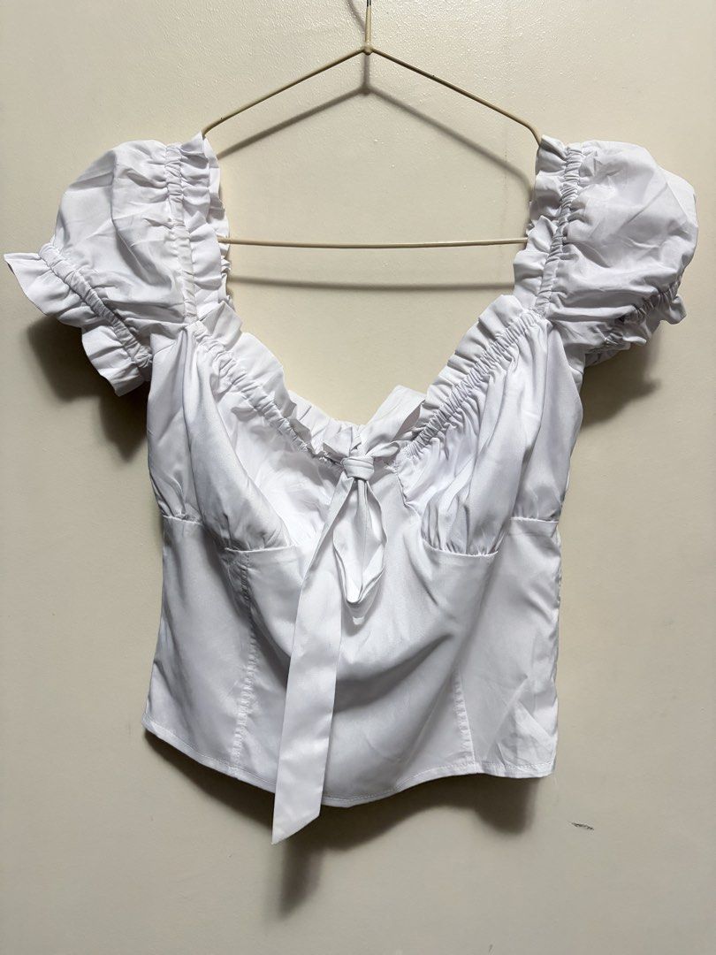 White Short Sleeve Ruffle Blouse with Front Tie (Category: Blouses) located in Quezon City. Submitted by j.steffy (Listing ID 1467322217, Image 1). Description: - Color: White - Style: Crop top blouse - Neckline: Sweetheart with ruffle collar details - Sleeves: Short puff sleeves with elastic ruching - Details: Long ribbon tie at the center front bust - Material: Smooth, comfortable fabric - Fit: True to size - Perfect for pairing with high-waist