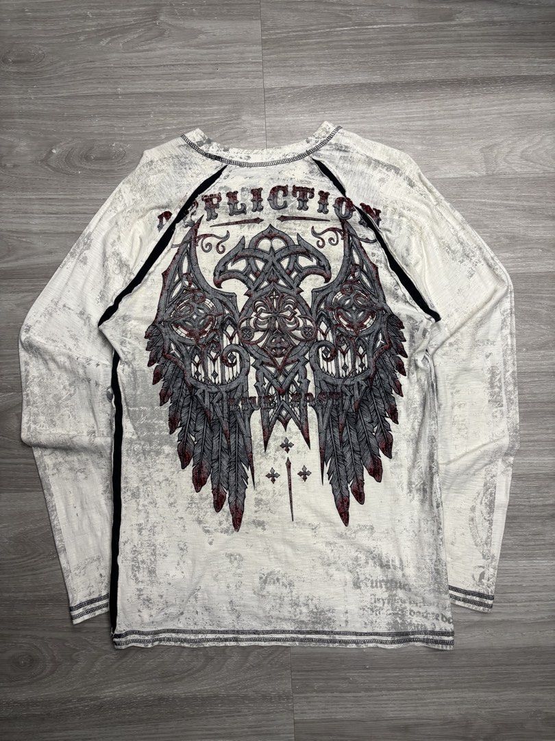 Y2K Affliction Sweater (Category: Tshirts & Polo Shirts ) located in Pagadian. Submitted by afterwearph (Listing ID 1467338274, Image 1). Description: - Brand: Affliction - Color: Grey and white with contrasting black side panels - Style: Long sleeve crew neck with raw edges / Heavy metal Y2K aesthetic - Graphics: Large 'Live Fast' and cross design on chest, massive detailed wing graphic on the back - Shipping: Ships via J&T Express or local PH c