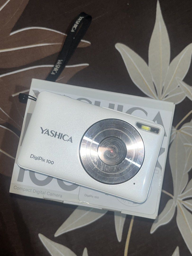 Yashica DigiPix 100 | READ DESCRIPTION (Category: Cameras) located in Mandaluyong City. Submitted by rockstain (Listing ID 1467253427, Image 1). Description: - Model: Yashica DigiPix 100 Compact Digital Camera (White) - Included: Original box and branded wrist strap (not included: charger) - Specs: f=7.36mm lens, F/3.2 aperture, up to 16x digital zoom - 10/10 Condition: Good working condition with minor fingerprint smudges on the rear screen, lig