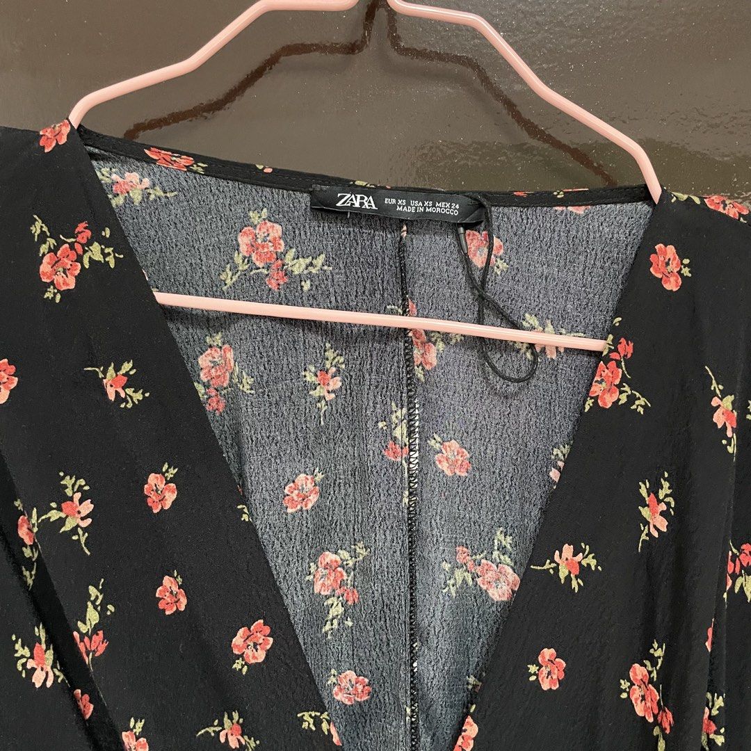 Zara Black Floral Wrap Blouse (Category: Blouses) located in Pasay City. Submitted by lovedbyzea (Listing ID 1467337593, Image 2). Description: - Linen-blend fabric - Brand: Zara - Style: Long sleeve wrap blouse with front gathered knot detail - Pattern: Red floral print with green leaves on black fabric - Neckline: V-neck - Size: EUR XS / USA XS - Origin: Made in Morocco - Lightweight and comfortable fabric.