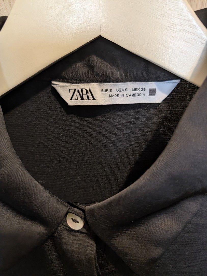 Zara Womens Black Satin Collared Blouse (Category: Blouses) located in Manila. Submitted by cart_rd (Listing ID 1467203515, Image 3). Description: - Brand: Zara - Color: Black - Size: Small (S) - Material: Satin - Design: Short dolman sleeves, collared neckline, front button placket with hidden buttons, and a box pleat on the back yoke for a relaxed fit - Origin: Made in Cambodia - pls see last photo for minor wear sign, tiny snag hole on the col
