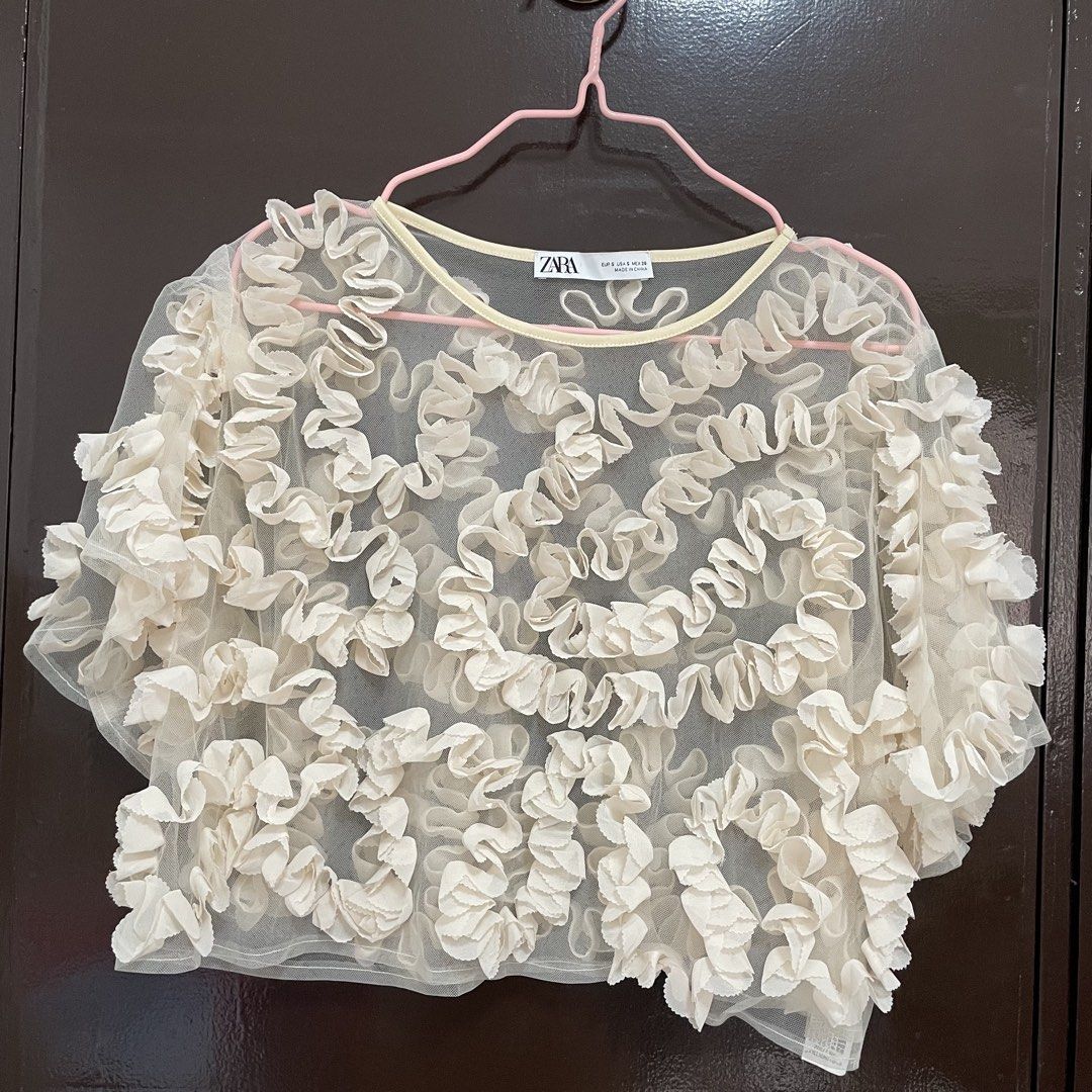 Zara Mesh Ruffle Top Cream Size S (Category: Blouses) located in Pasay City. Submitted by lovedbyzea (Listing ID 1467342551, Image 1). Description: - can fit S-M - Brand: Zara - Size: Small (Made in China) - Color: Cream with soft yellowish contrast trim - Material: Lightweight, sheer mesh fabric - Design: All-over ruffles, short sleeves, round neckline - Styling: Best worn layered over a camisole or bralette.