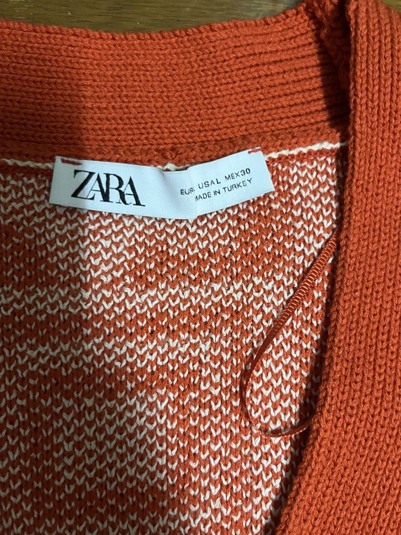 Zara Orange Flower Pattern Knit Cardigan (Category: Coats, Jackets and Outerwear) located in Mandaluyong City. Submitted by dadsmiddlechild (Listing ID 1467353274, Image 2). Description: - Brand: Zara - Size: L - Color/Pattern: Orange and white with bold floral and geometric checkerboard design - Details: V-neck, white front buttons, solid orange and cream ribbed hem, cuffs, and collar - Material: Thick knit, warm and comfortable - Origin: Made i