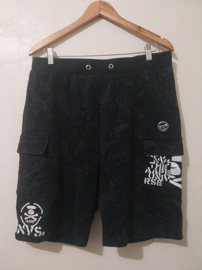 Aape Authentic Black Camo Cargo Shorts (Category: Shorts) located in Davao. Submitted by thegraildept2026 (Listing ID 1467547897, Image 1). Description: - Brand: Aape - Color: Black with subtle tonal camo print - Features: White graphic prints on hem and back pocket - Details: Metal Aape logo button, side cargo pockets, and Velcro patch with Aape text - Fit/Style: Drawstring eyelets along waistband, casual streetwear piece.