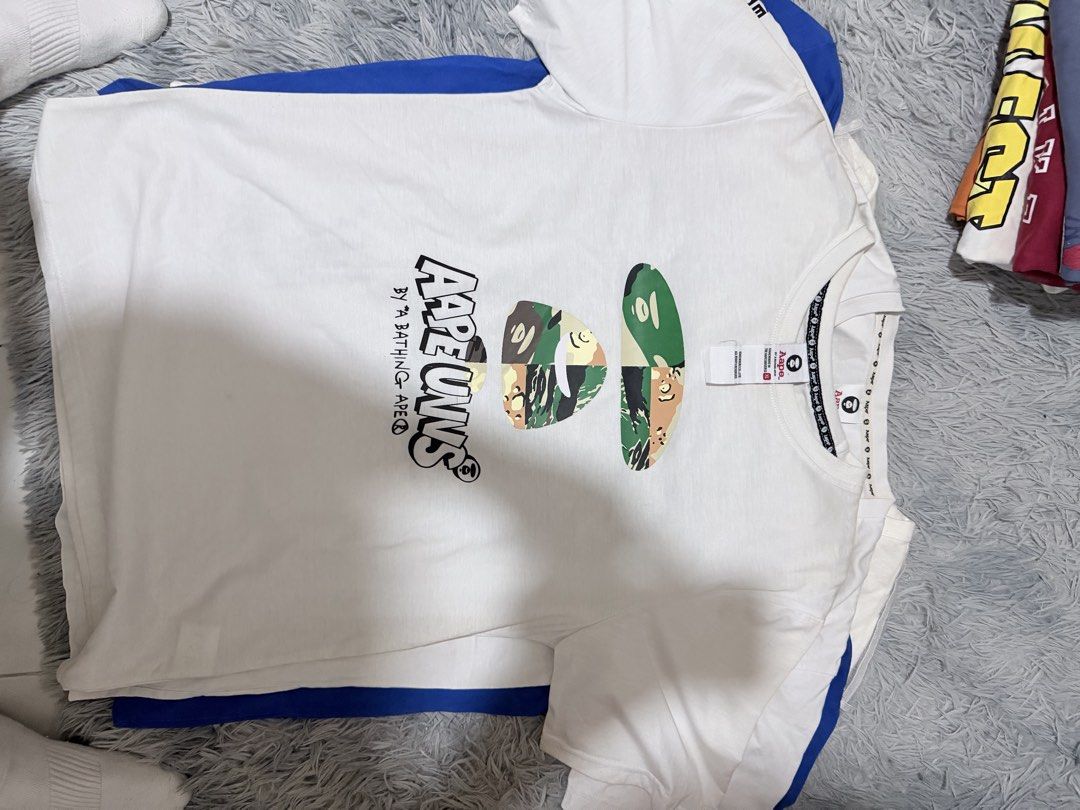 AAPE By A Bathing Ape White T-Shirt (Category: Tshirts & Polo Shirts ) located in Manila. Submitted by m1ggo (Listing ID 1467533376, Image 1). Description: - Brand: AAPE By A Bathing Ape - Color: White - Size: XL - Design: Large AAPE UNVS front graphic print - Details: Classic crew neck with branded inner taping and embroidered logo patch on the hem - Condition: Clean, great streetwear piece.