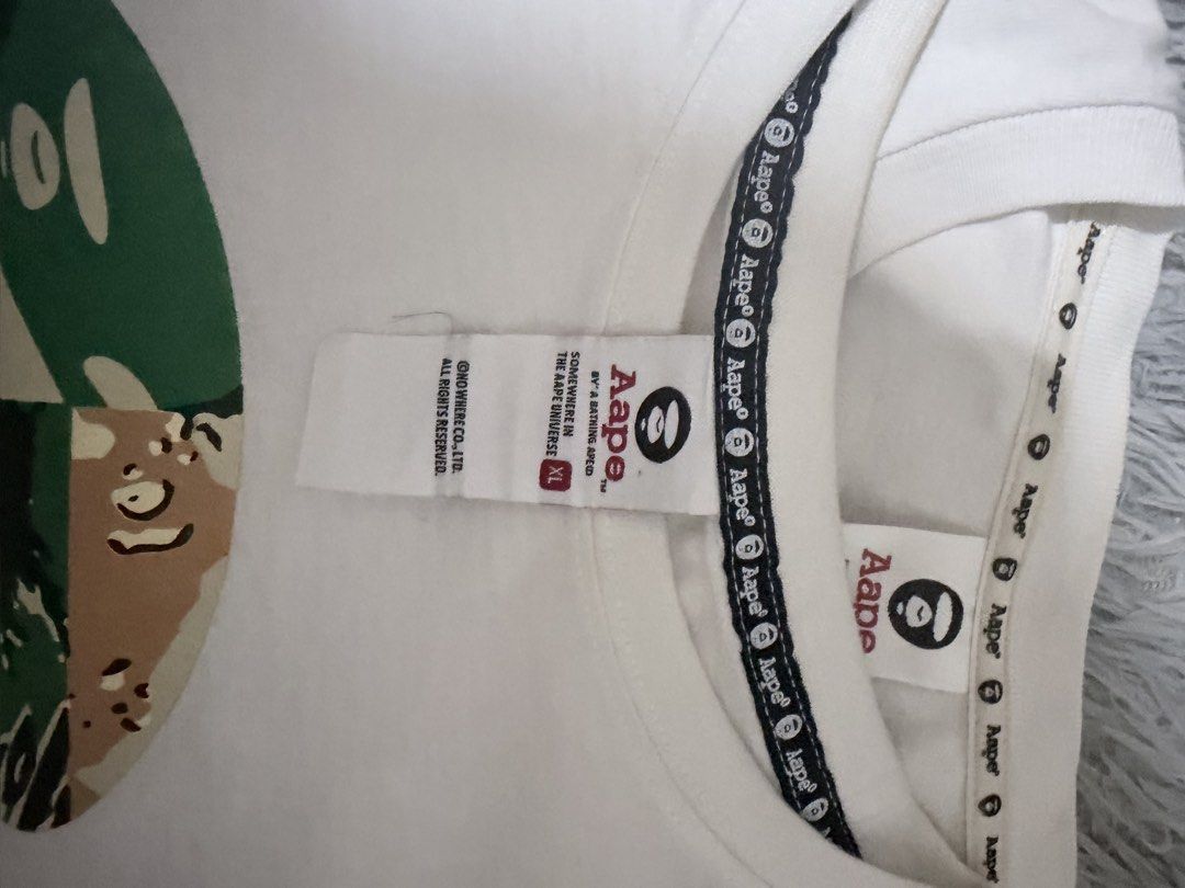 AAPE By A Bathing Ape White T-Shirt (Category: Tshirts & Polo Shirts ) located in Manila. Submitted by m1ggo (Listing ID 1467533376, Image 2). Description: - Brand: AAPE By A Bathing Ape - Color: White - Size: XL - Design: Large AAPE UNVS front graphic print - Details: Classic crew neck with branded inner taping and embroidered logo patch on the hem - Condition: Clean, great streetwear piece.