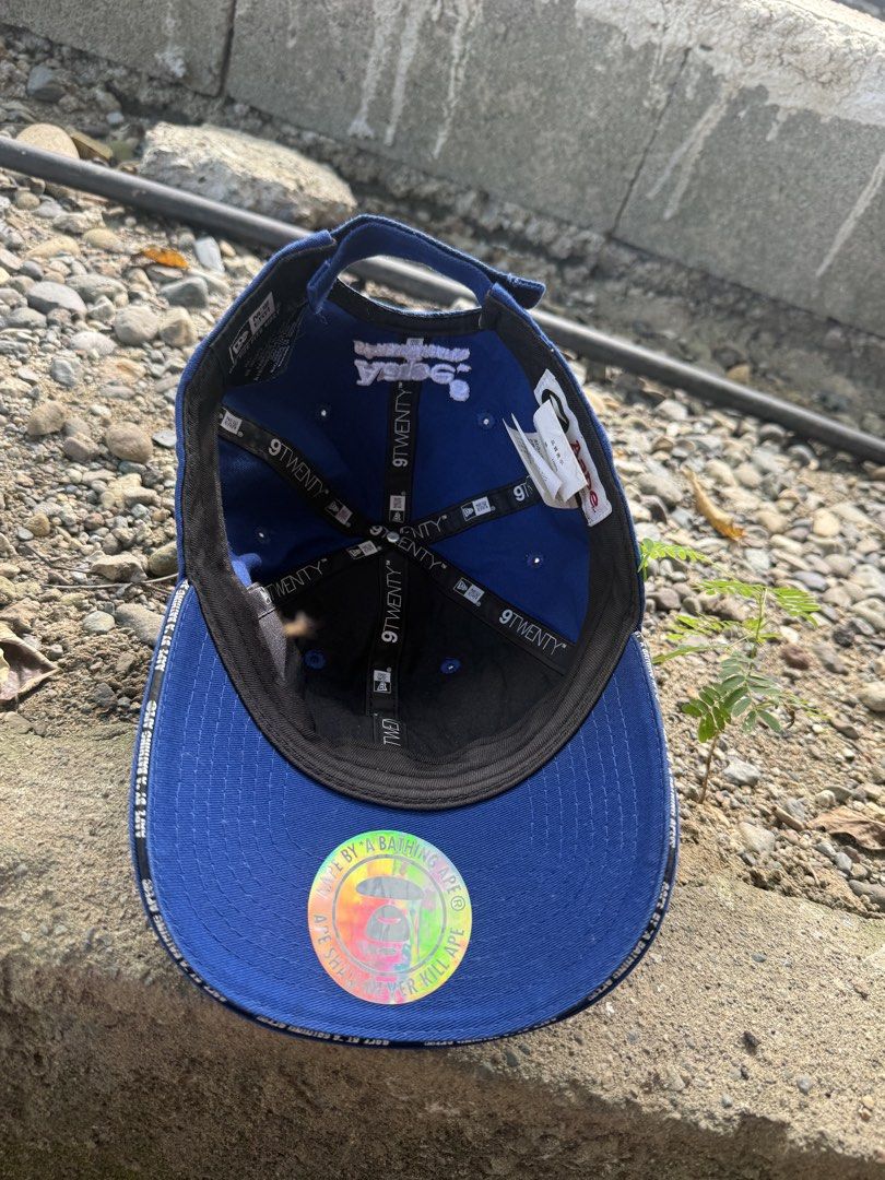 Aape x New Era 9TWENTY Blue Cap (Category: Caps & Hats) located in Burgos, Ilocos Norte. Submitted by copthrift (Listing ID 1467371686, Image 2). Description: - Official Aape x New Era collaboration - Style: Classic 9TWENTY adjustable strapback - Color: Royal Blue cotton - Details: White Aape front logo, New Era side embroidery, and back text branding - Authenticity: Includes original interior tags and brim holographic sticker - Size: One size fi