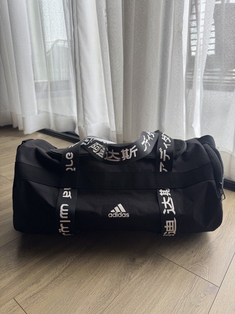 Adidas Black Duffel Bag Multi-Language Logo (Category: Sling Bags) located in Davao. Submitted by Tineeee. (Listing ID 1467372734, Image 3). Description: - Brand: Adidas - Color: Classic Black with bold global lettering straps - Condition: Clean inside and out, smooth-working zippers - Storage: Very spacious, perfect for gym gear, sports equipment, or weekend travel - Comfort: Includes dual carry handles and an adjustable, padded shoulder strap.