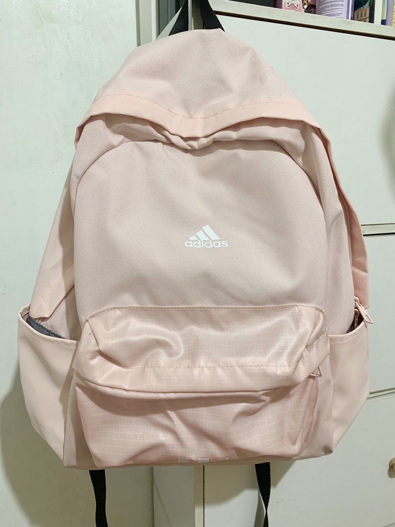 Adidas Pink Backpack (Category: Backpacks) located in Roxas City. Submitted by knewave (Listing ID 1467528827, Image 1). Description: - Color: Soft pink with a white Adidas logo - Pockets: Front zipper pocket with a subtle grid pattern and convenient side slip pockets for water bottles - Straps: Top carry handle and black adjustable shoulder straps .