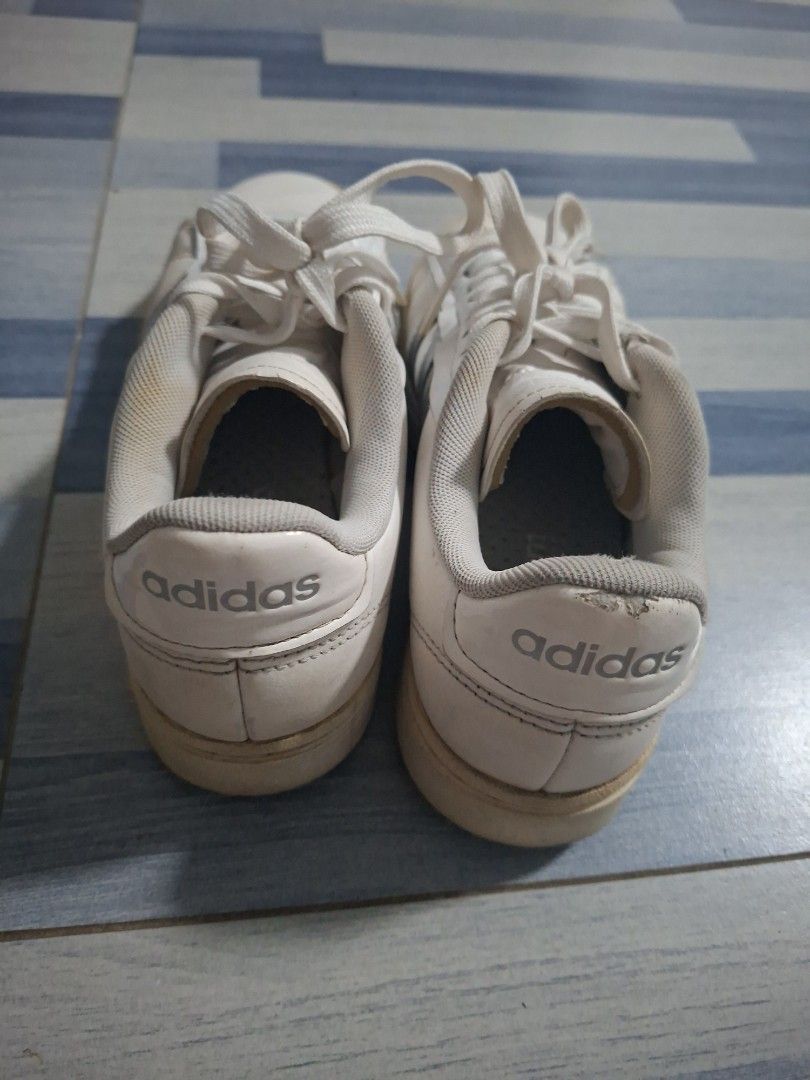 Adidas White Casual Sneaker (Category: Sneakers) located in Manila. Submitted by ninyagauri24333 (Listing ID 1467480435, Image 2). Description: - Brand/Model: Classic white Adidas sneakers with stylish silver stripes and laces - Comfort & Grip: Features padded ankle collars for extra comfort and textured rubber outsoles for good traction - Condition: Shows visible signs of wear on the leather uppers and soles, with slight peeling on the collar of