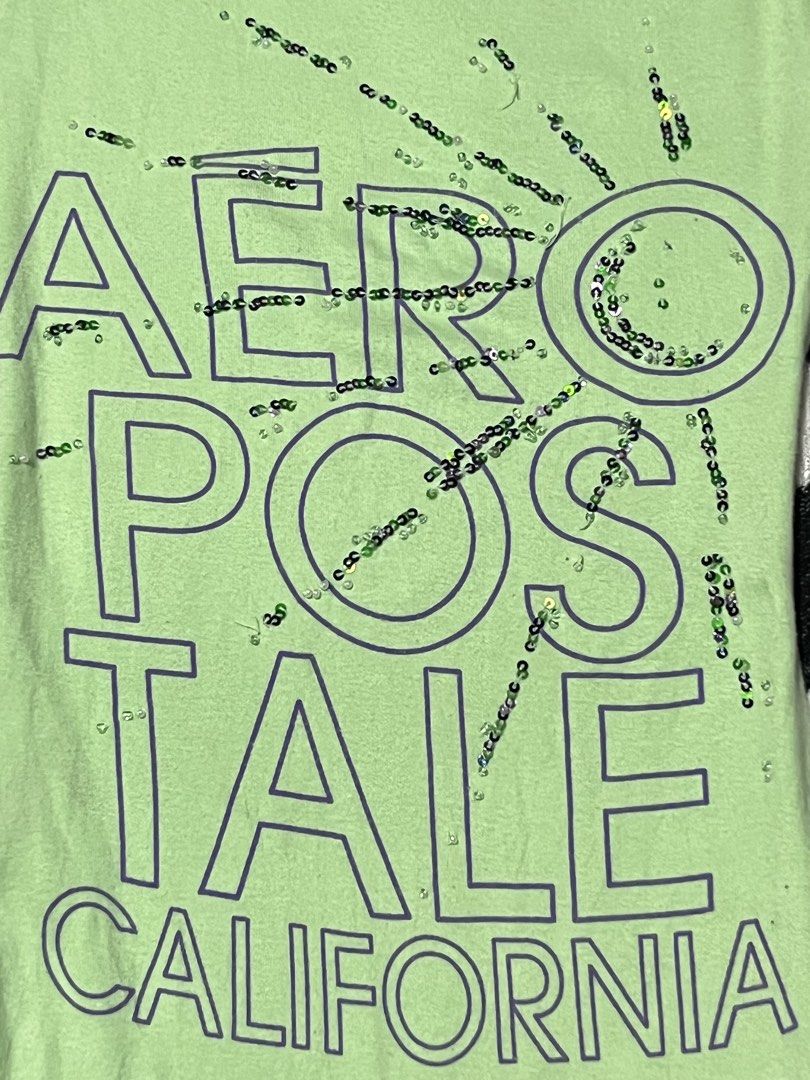Aeropostale Stretch Green California Sequin Tank Top Medium (Category: Sleeveless) located in Manila. Submitted by y2kcloset_ (Listing ID 1467476621, Image 3). Description: - Brand: Aeropostale - Size: Medium - Color: Green - Material: Soft cotton and spandex blend with plenty of stretch - Design: 'Aeropostale California' graphic text with subtle sequin accents on the front - Neckline: Scoop neck with a comfortable tagless printed collar label - 