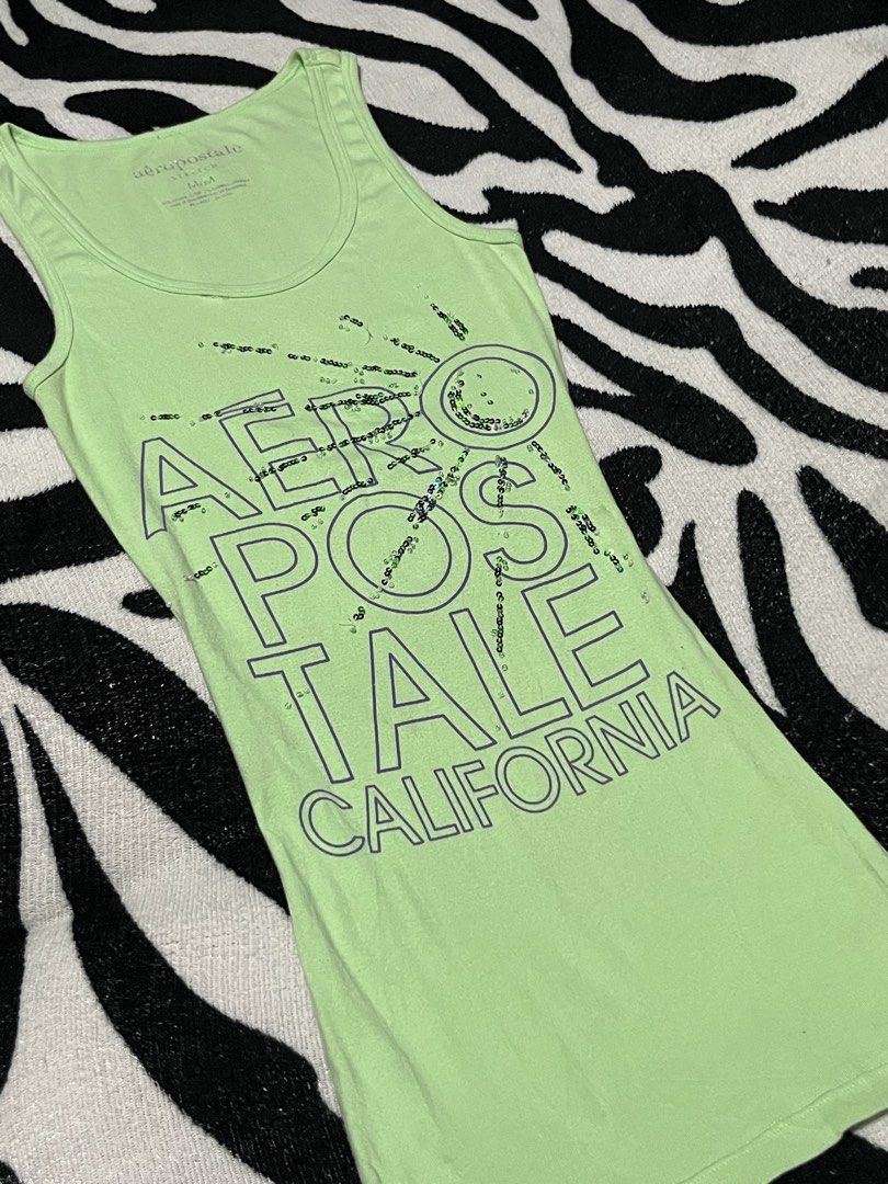 Aeropostale Stretch Green California Sequin Tank Top Medium (Category: Sleeveless) located in Manila. Submitted by y2kcloset_ (Listing ID 1467476621, Image 2). Description: - Brand: Aeropostale - Size: Medium - Color: Green - Material: Soft cotton and spandex blend with plenty of stretch - Design: 'Aeropostale California' graphic text with subtle sequin accents on the front - Neckline: Scoop neck with a comfortable tagless printed collar label - 