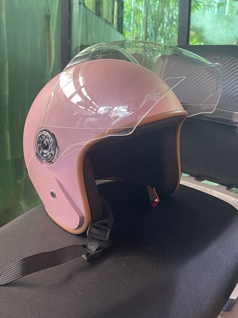 AKA Pink Motorcycle Half-Helmet with Clear Visor (Category: Bicycles) located in San Pablo. Submitted by vrmthrsainz (Listing ID 1467421395, Image 2). Description: - Brand: AKA Motorcycle Helmet - Color: Matte pink finish with stylish brown trim - Visor: Clear, moves up and down smoothly - Interior: Comfortable black padding - Safety: Certified product safety sticker on the back - Closure: Adjustable chin strap with quick-release buckle.