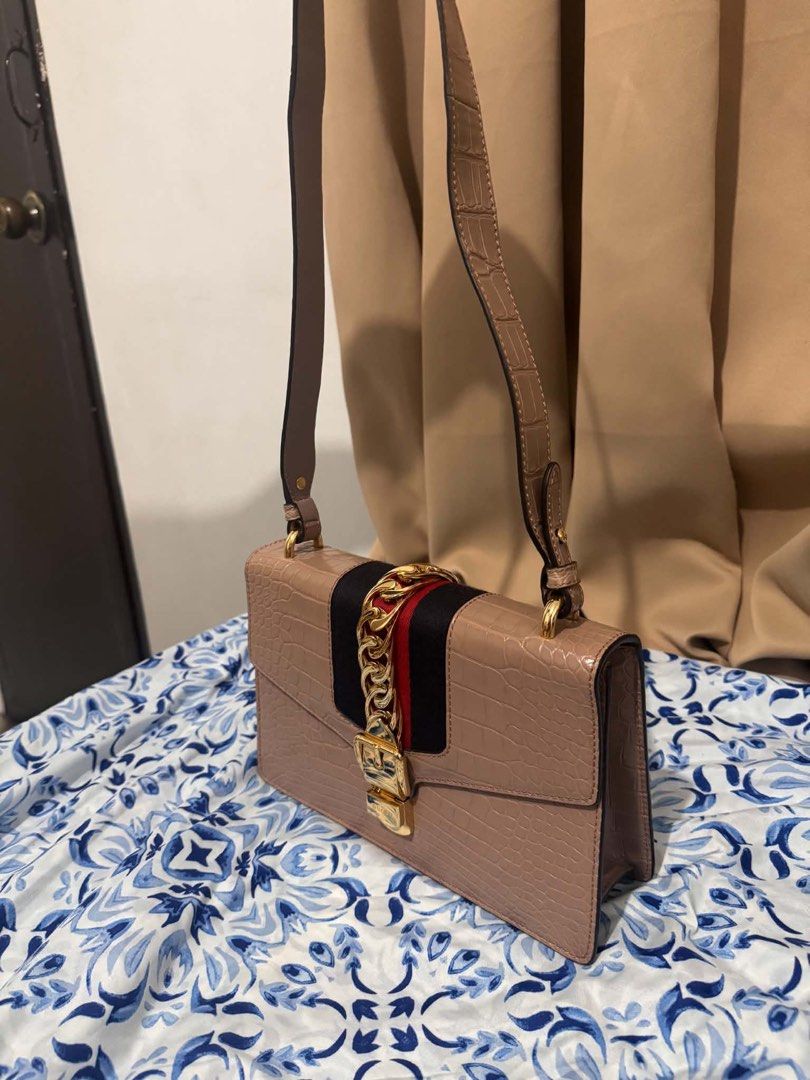 Authentic Gucci Sylvie Beige Exotic Crocodile Shoulder Bag (Category: Luxury Bags & Wallets) located in San Pedro. Submitted by rjgrat (Listing ID 1467423320, Image 3). Description: - Brand: Gucci - Style: Sylvie Shoulder Bag - Material: Beige exotic crocodile leather - Design: Signature navy and red web stripe with chunky gold-tone chain and buckle lock - Structure: Structured shape with a convenient top handle strap - Condition: Never used, goo