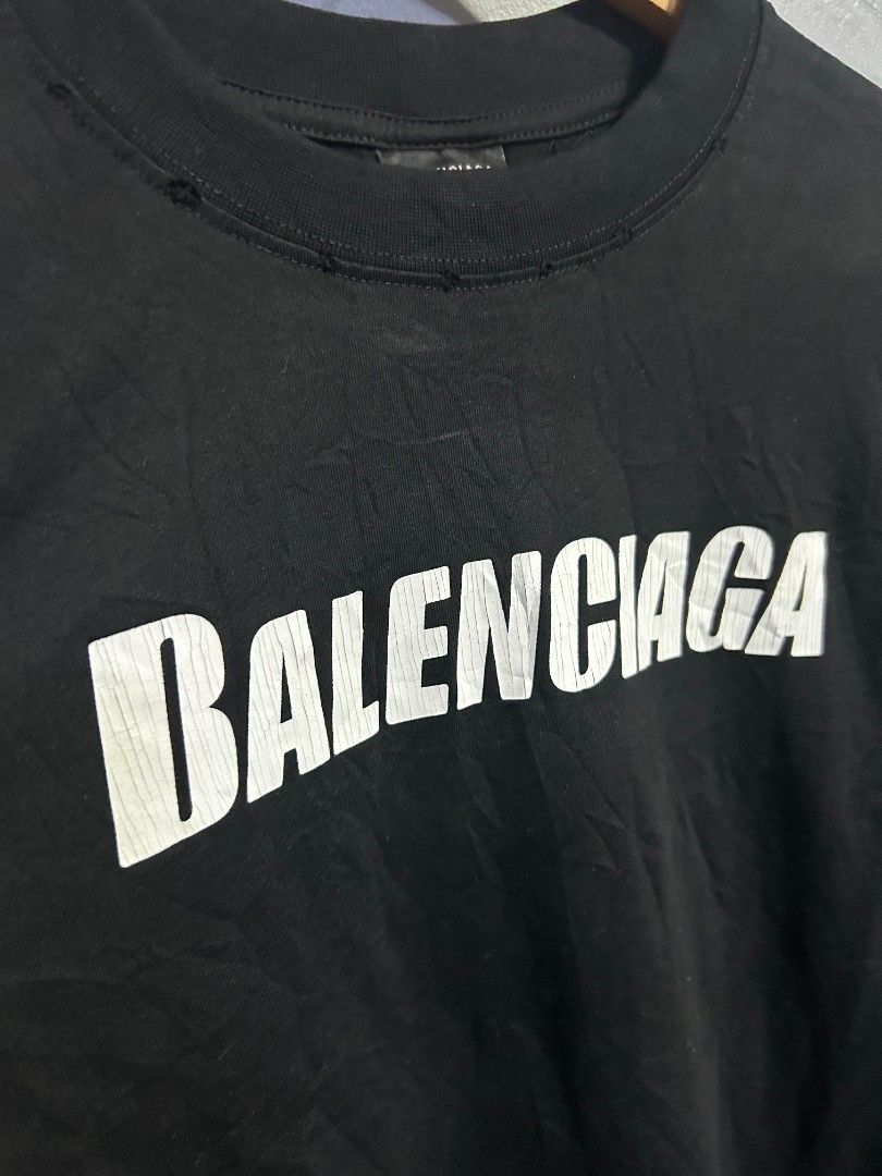 Balenciaga Black Long Sleeve Tee Size L (Category: Luxury Apparel) located in Manila. Submitted by marjoriete27817 (Listing ID 1467523780, Image 3). Description: - Brand: Balenciaga - Color: Solid black - Size: L (Relaxed, oversized fit) 24*30 - Material: 100% cotton, made in Portugal - Design: Big white chest logo with slight cracking effect - Details: Ribbed crew neck with minor distressed collar detailing.