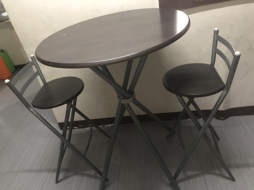 Bar Table with Chairs (Category: Tables & Sets) located in Cavite. Submitted by ai__chang (Listing ID 1467455625, Image 2). Description: - Modern bistro style set, ideal for small spaces and apartment living - Includes 1 round table with dark wood-look top and sturdy grey metal frame - Comes with 2 matching high chairs featuring wooden seats and backrests - Solid construction with clean, well-maintained surfaces.