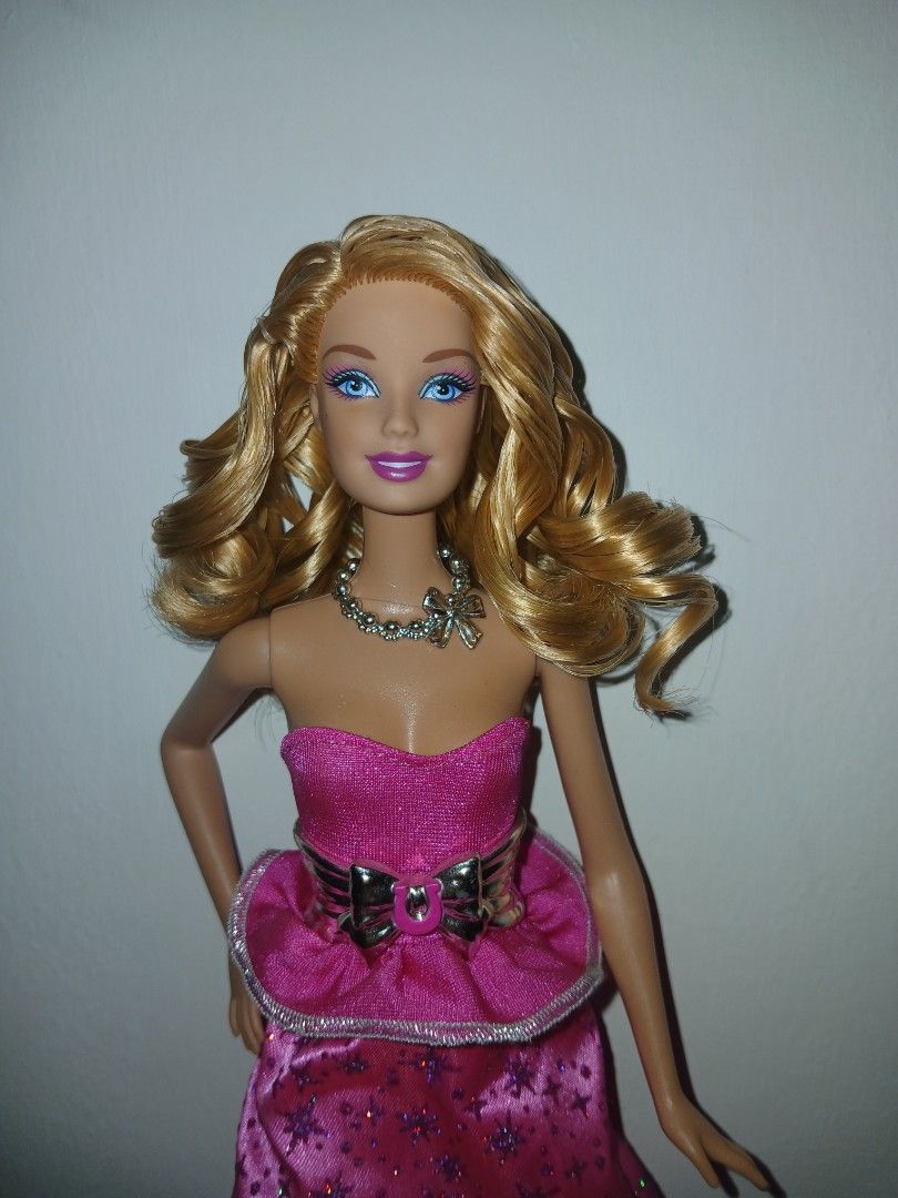Barbie & her sisters pony tale 2013 (rare type) (Category: Kids Toys) located in Subic. Submitted by frncnjntmr22 (Listing ID 1467564290, Image 2). Description: - Doll details: Blonde hair with bouncy curls, striking blue eyes - Outfit: Vibrant pink strapless dress with purple star patterns - Accessories: Metallic silver beaded necklace and matching silver bow belt - Footwear: Matching silver high-heeled shoes - Condition: Clean and fully intact 